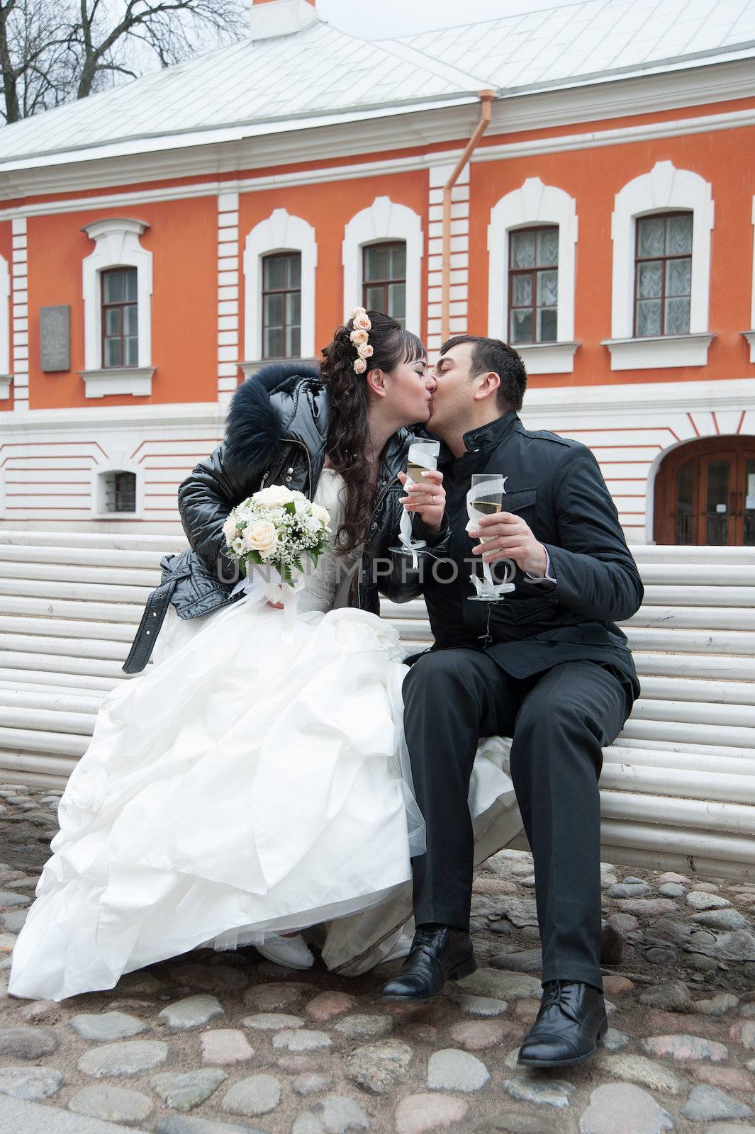 Bride and groom kissing on a park bench