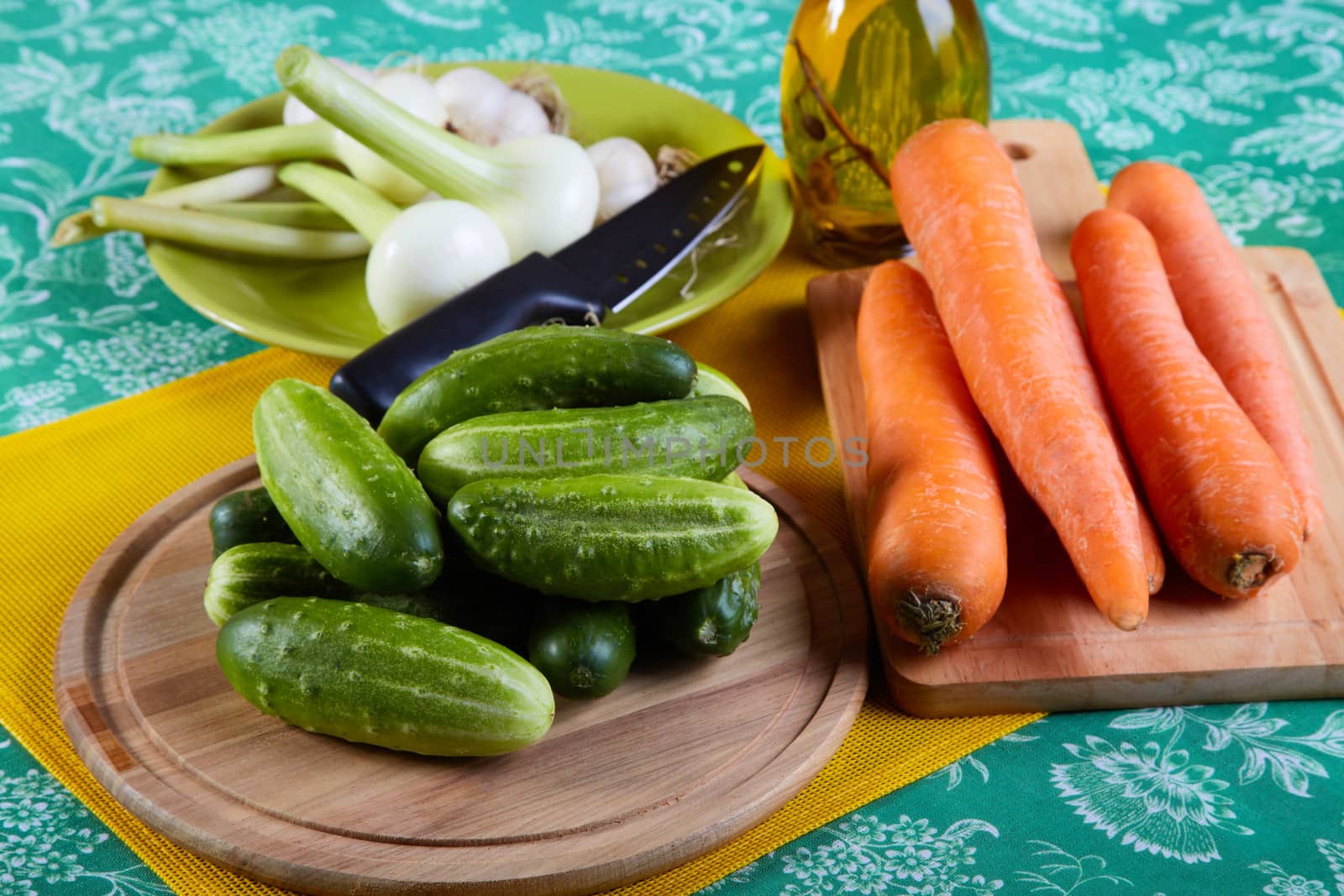 Green cucumbers with onions garlic and carrots on a kitchen table