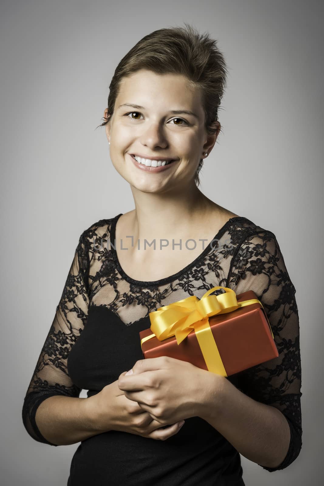 Young happy girl wearing evening dress holds a present