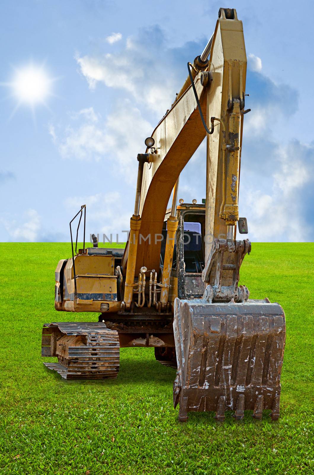 Track-type loader excavator machine on green grass field by pixbox77
