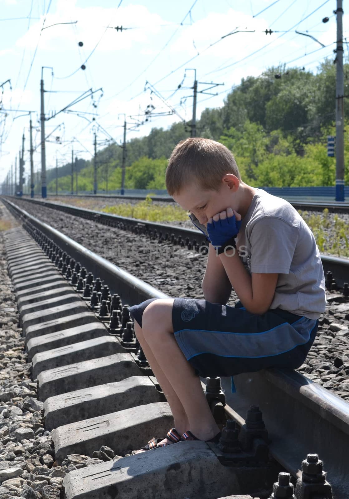 the sad boy sits on rails, having clasped the head hands