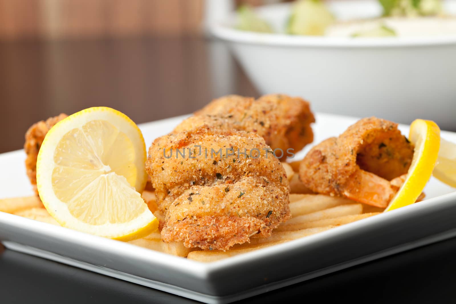 Fried shrimp and french fries plate garnished with lemon.