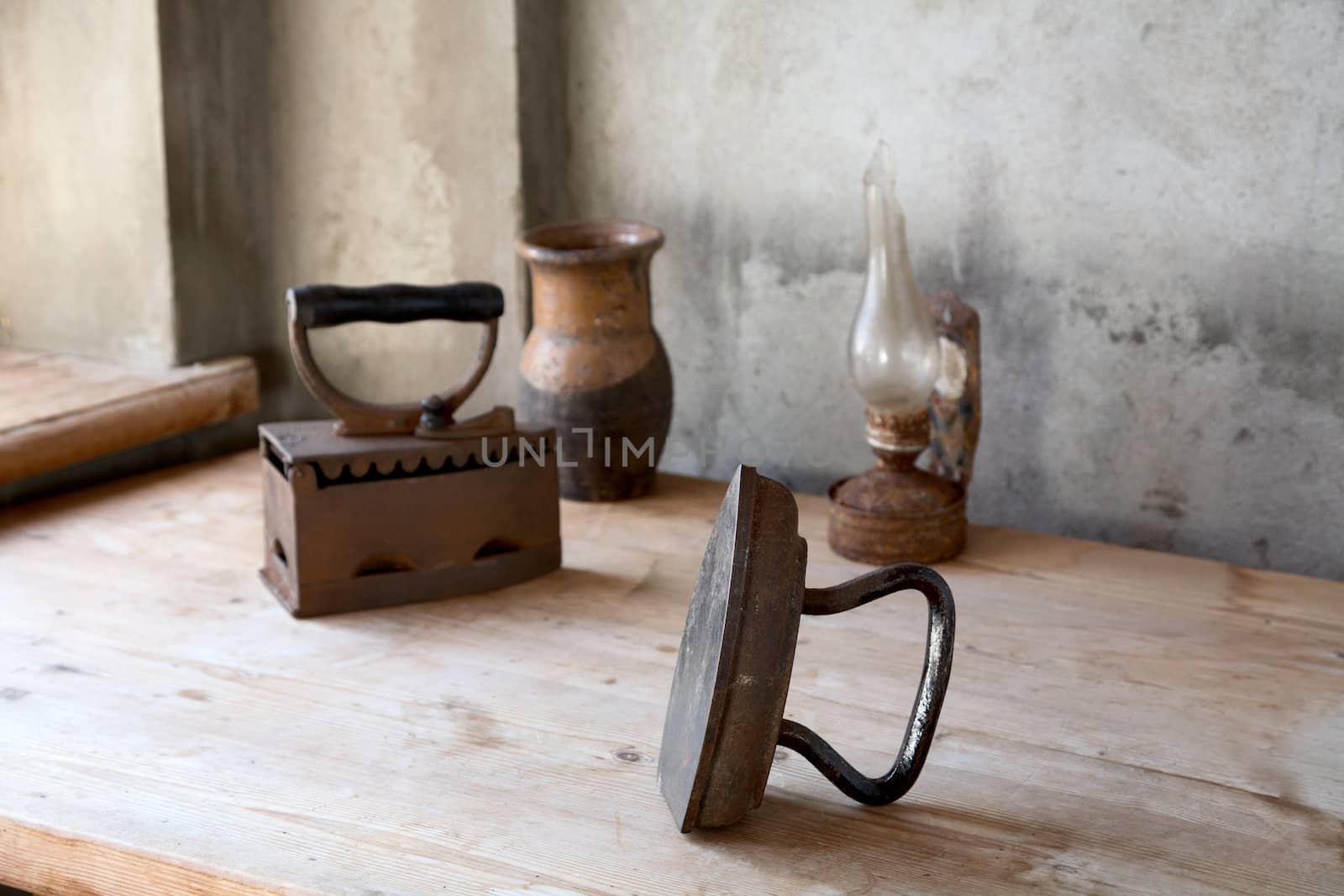 The old iron, oil lamp and jug on a wooden table