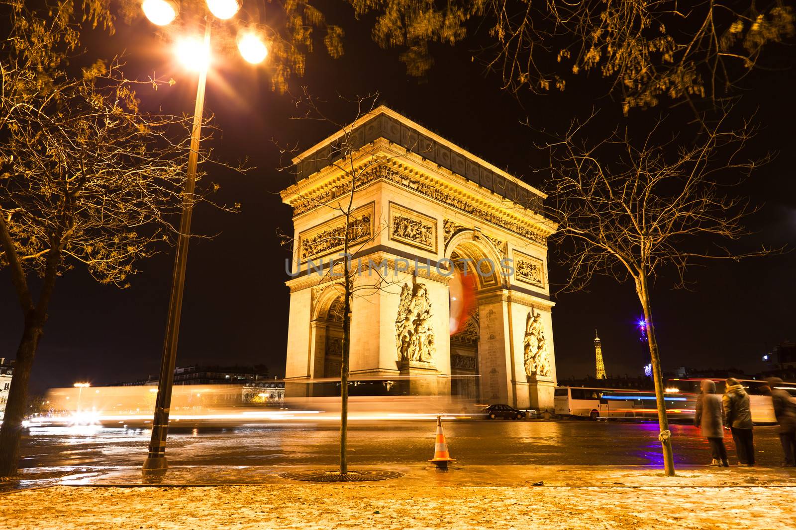 The Arc de Triomphe in Paris illuminated at night. 

