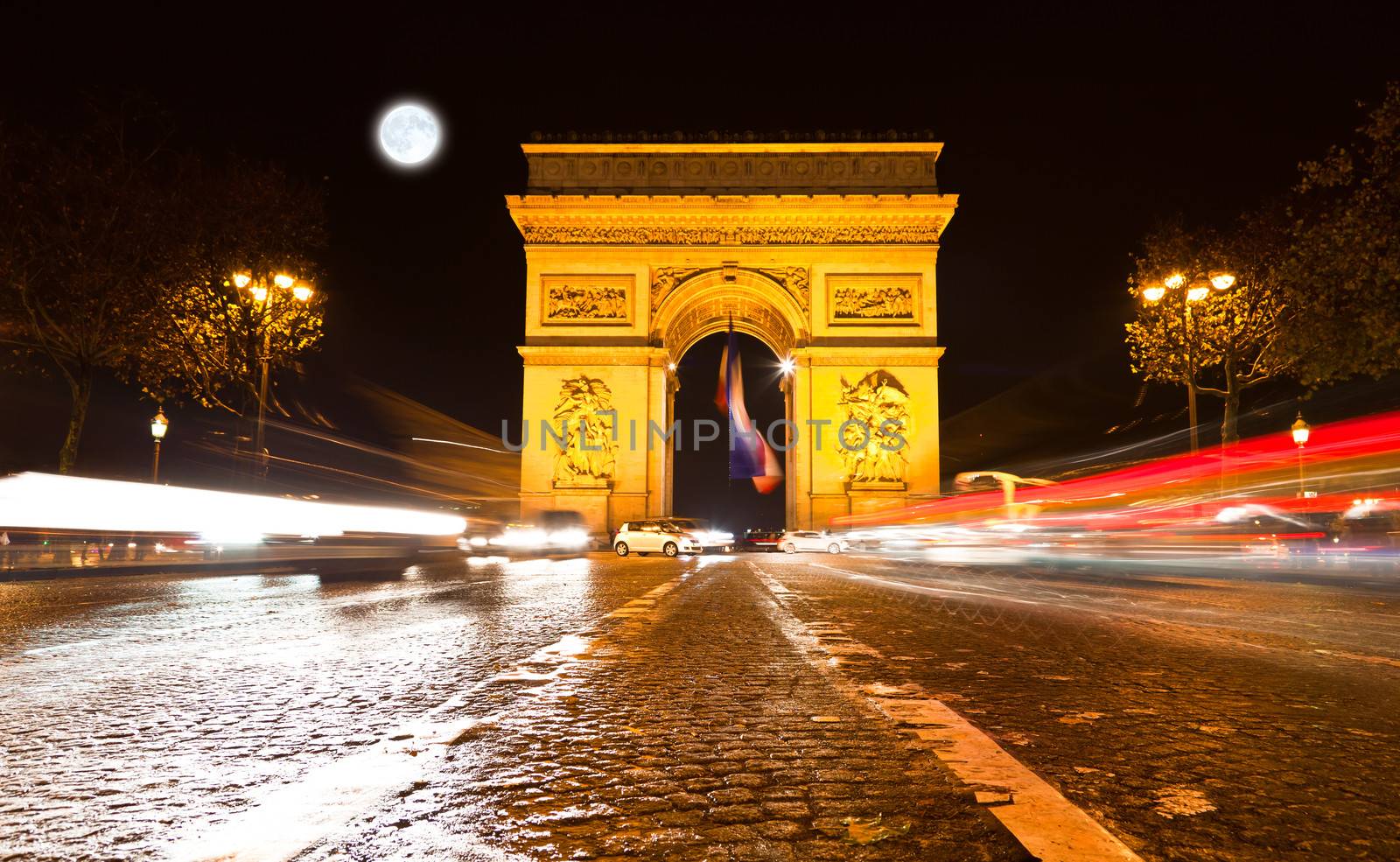 The Arc de Triomphe in Paris illuminated at night. 
