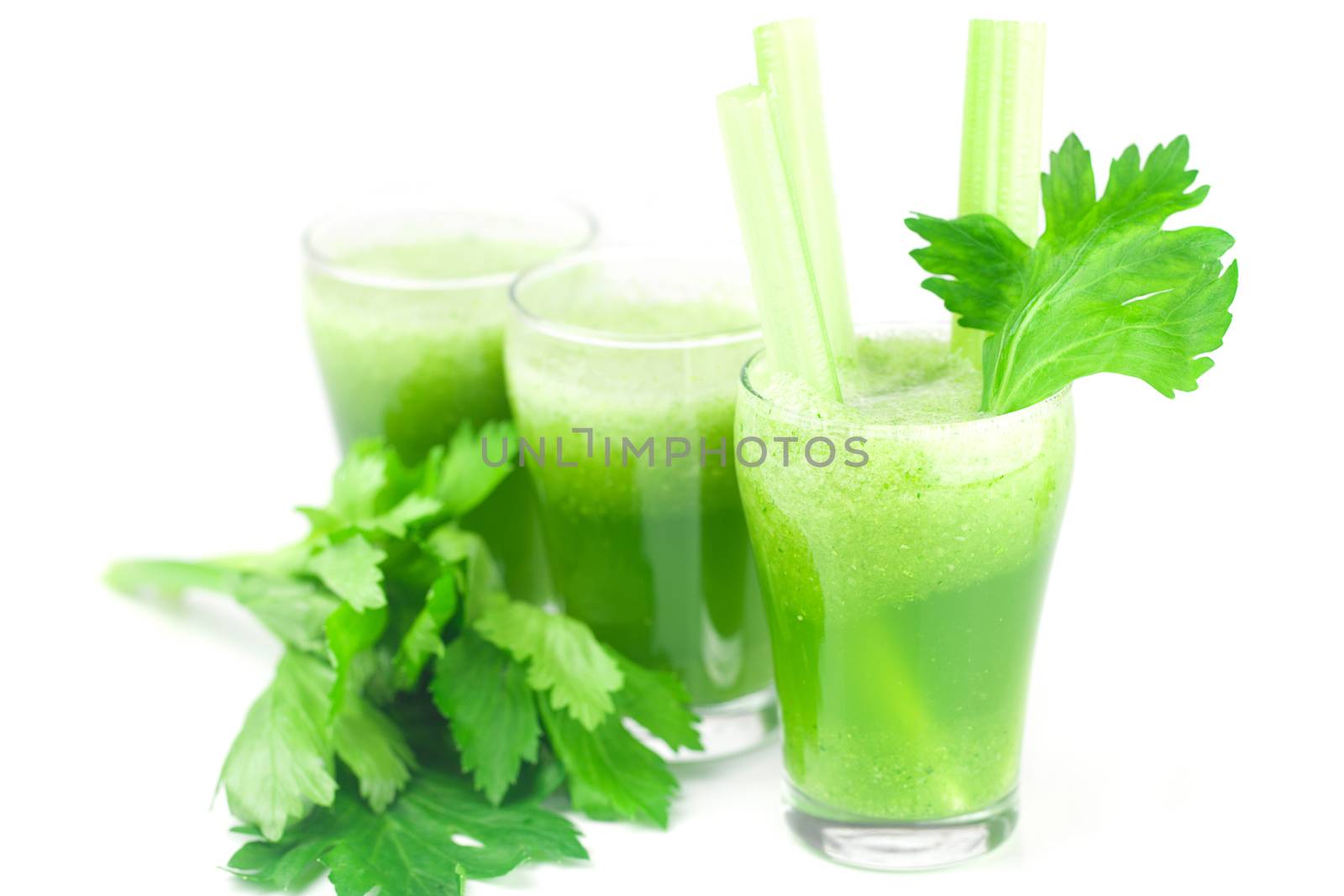 celery and three glasses with celery juice isolated on white