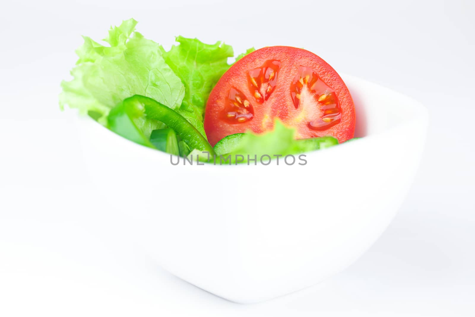 lettuce, tomato, cucumber and pepper in a bowl isolated on white by jannyjus