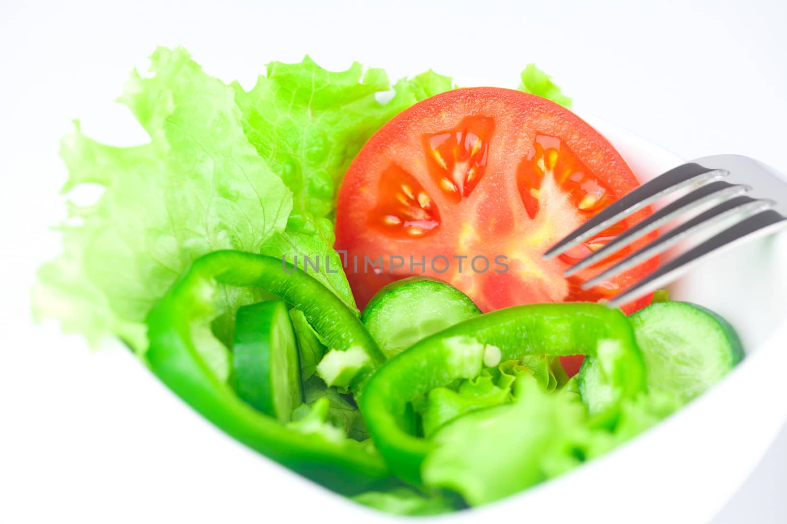 fork,lettuce, tomato, cucumber and pepper in a bowl isolated on white