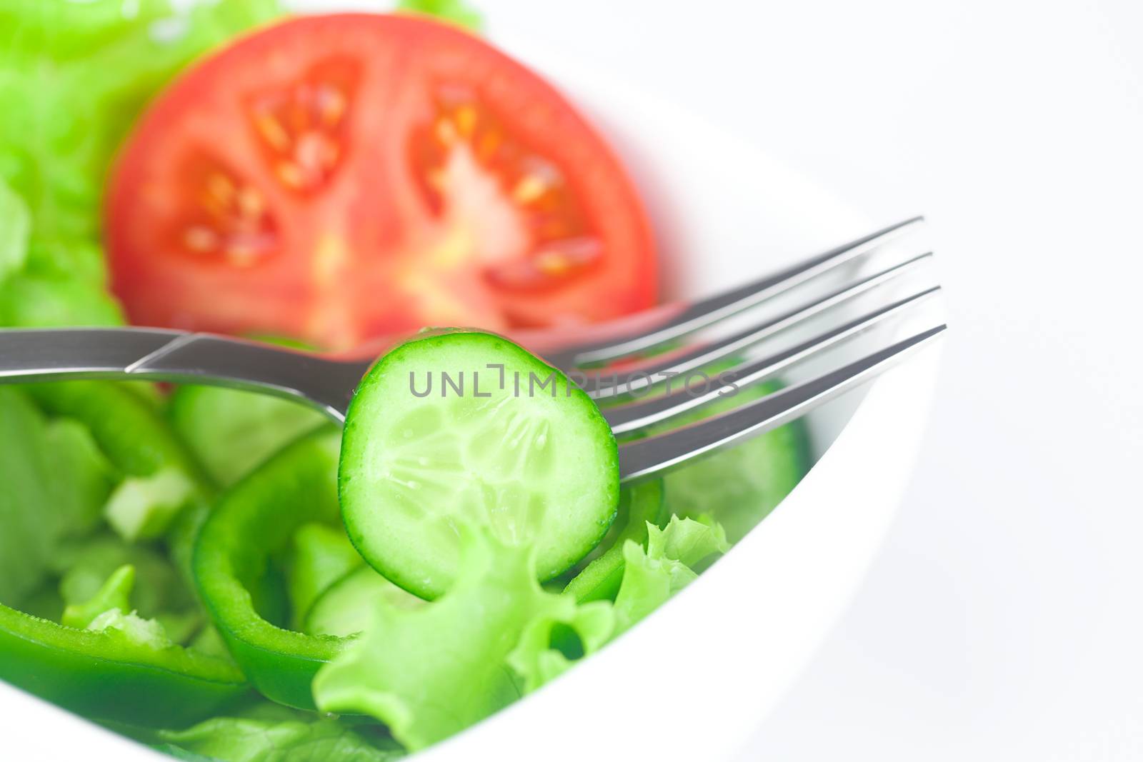fork,lettuce, tomato, cucumber and pepper in a bowl isolated on  by jannyjus