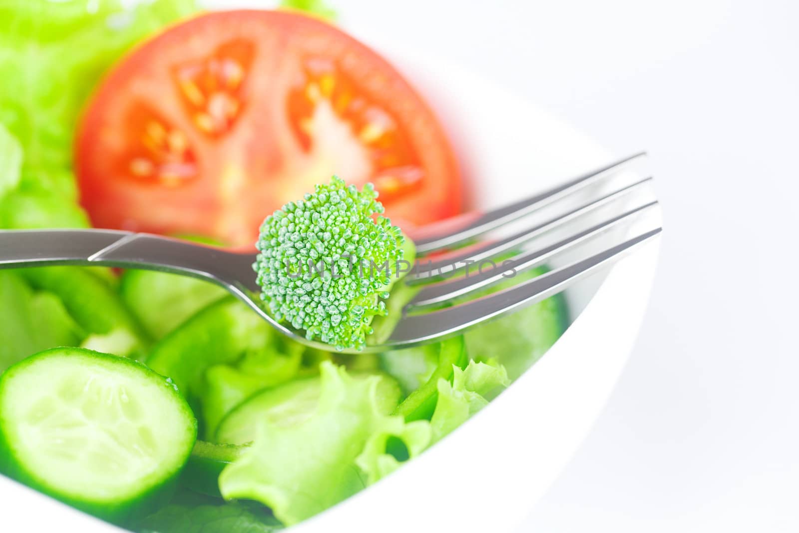 fork,broccoli,lettuce, tomato, cucumber and pepper in a bowl isolated on white
