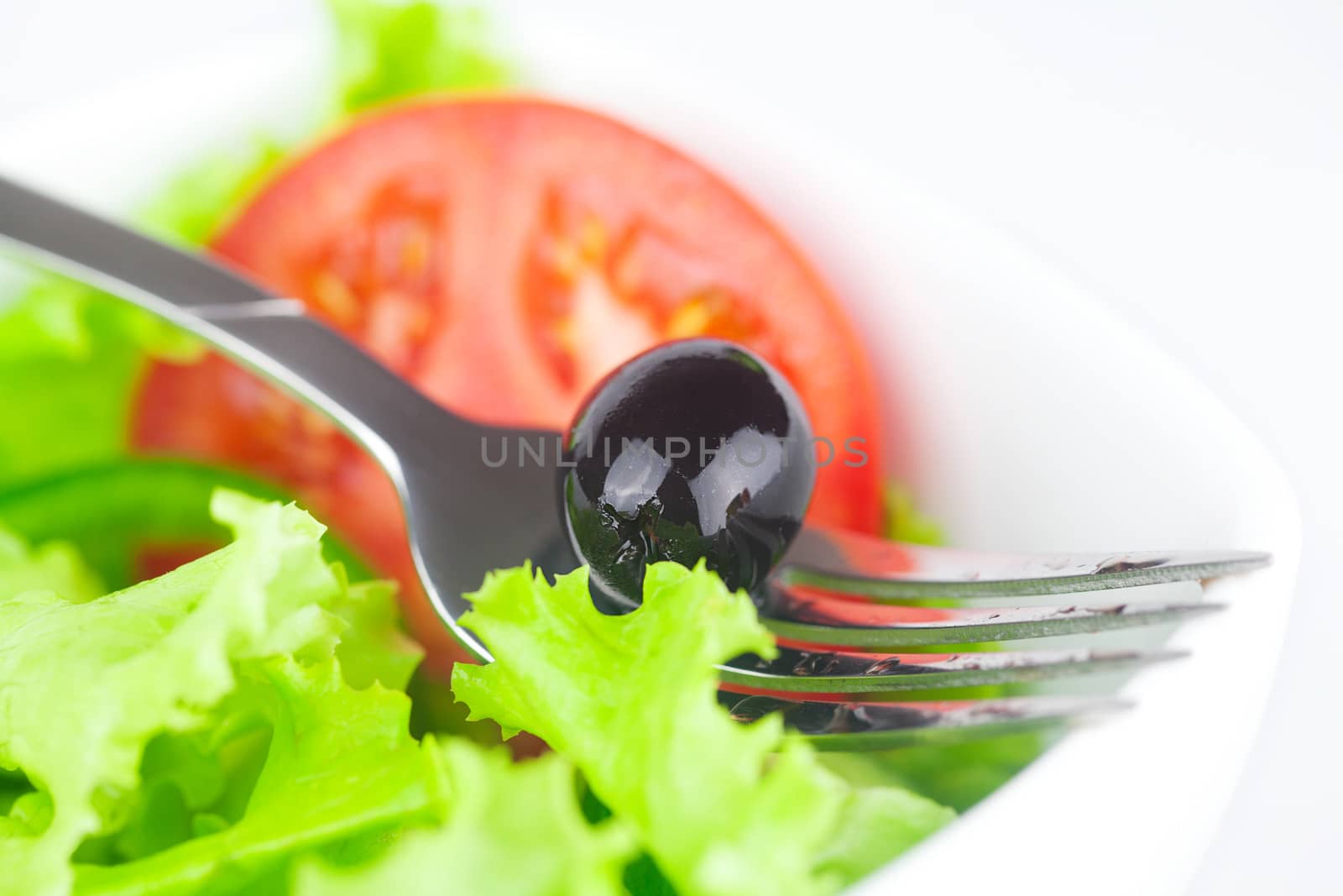fork,black olive,lettuce, tomato, cucumber and pepper in a bowl