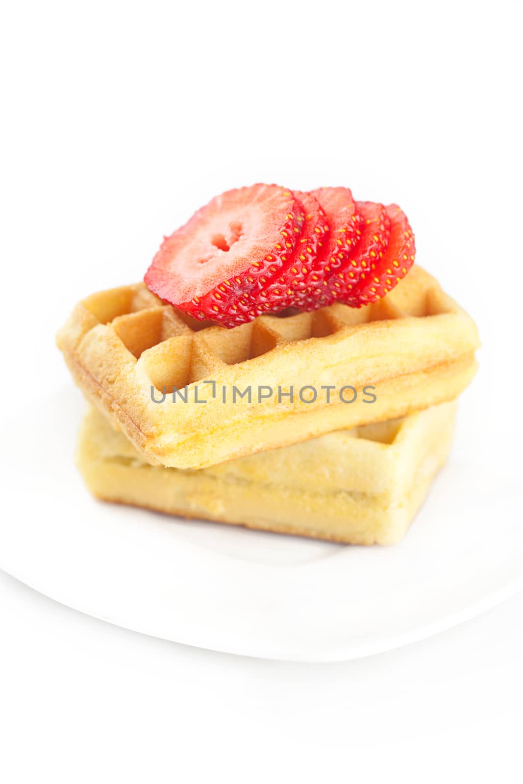 Belgian waffles and strawberry on a plate isolated on white