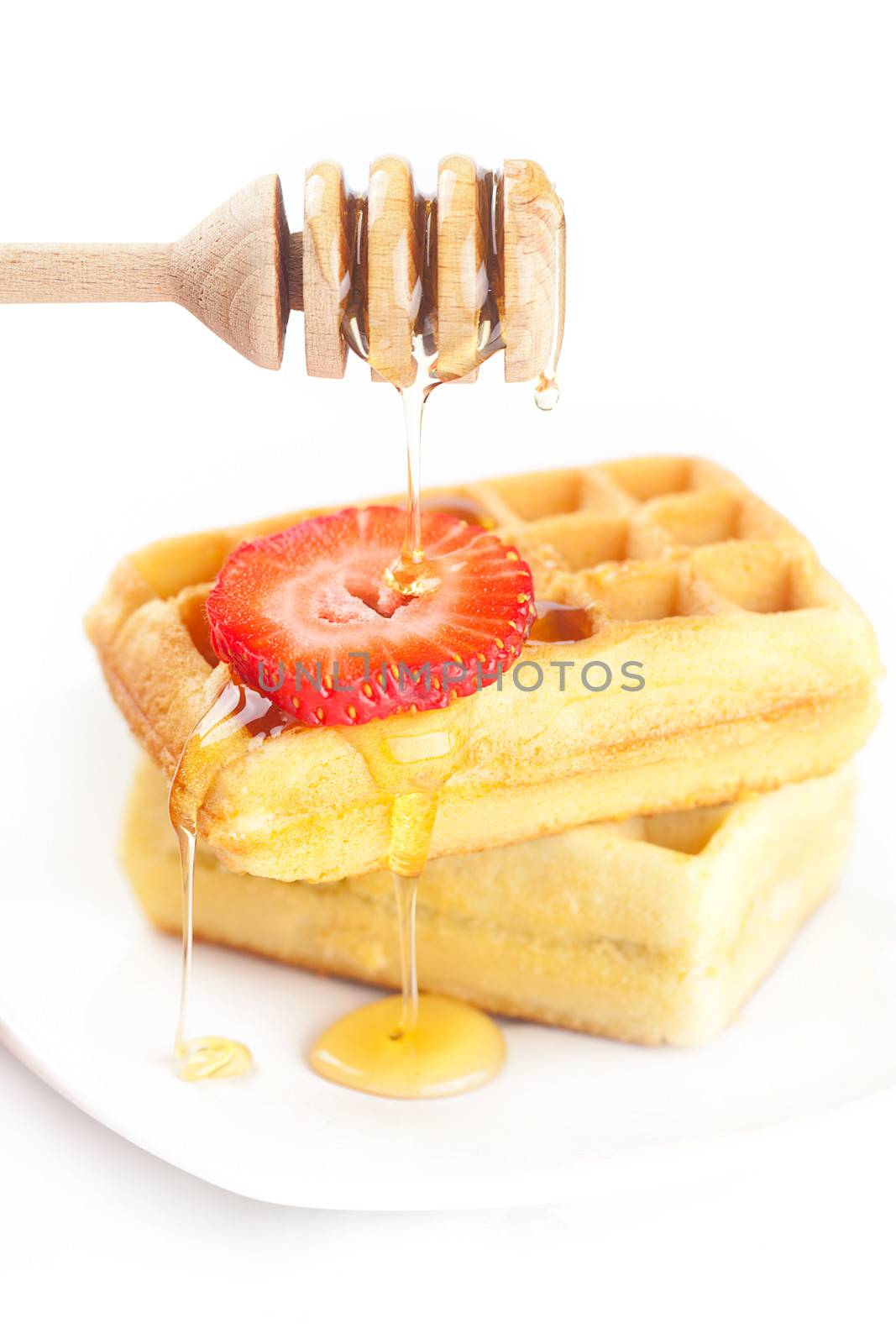 Belgian waffles and strawberries on a plate, stick for honey and honey isolated on white