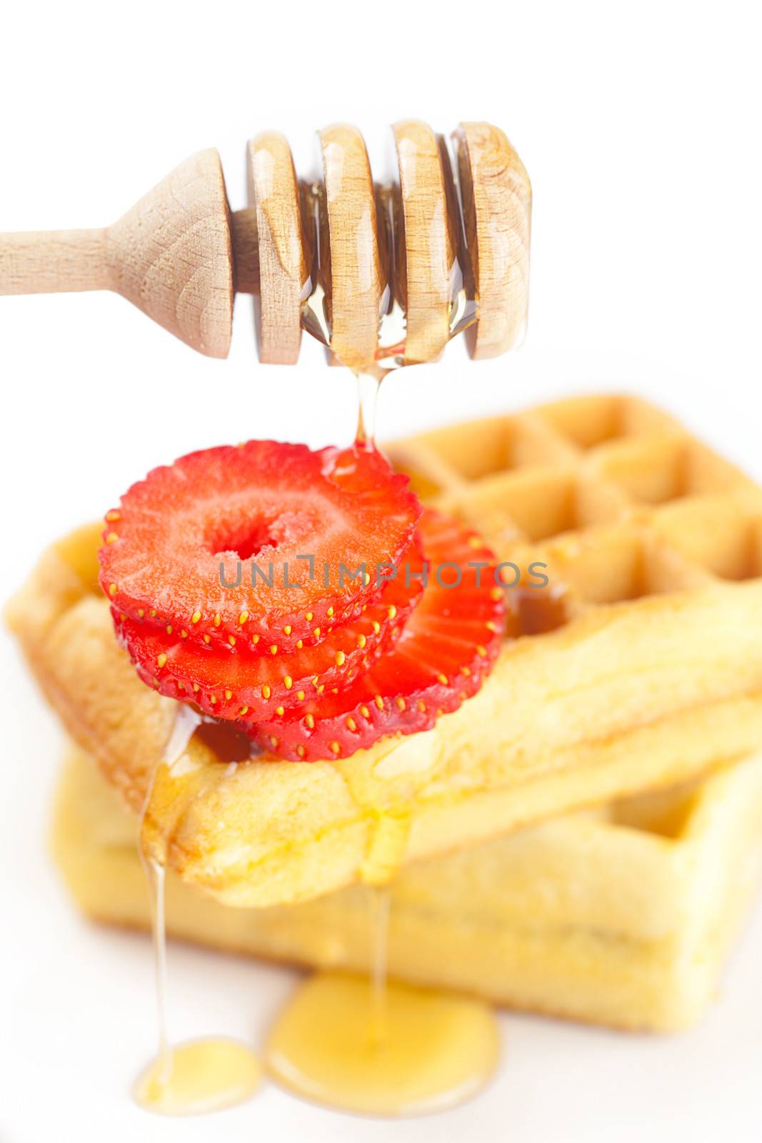 Belgian waffles and strawberries on a plate, stick for honey and honey isolated on white