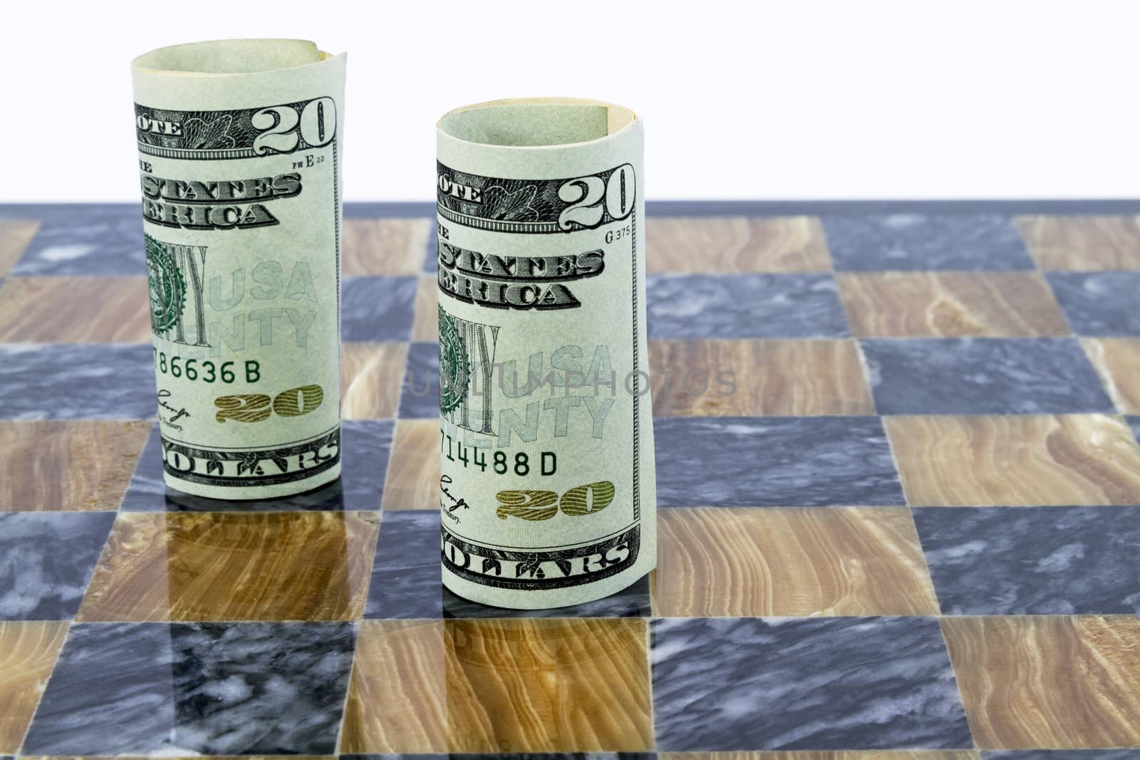 Game board of brown and black marble has two, rolled American dollars, standing upright.   