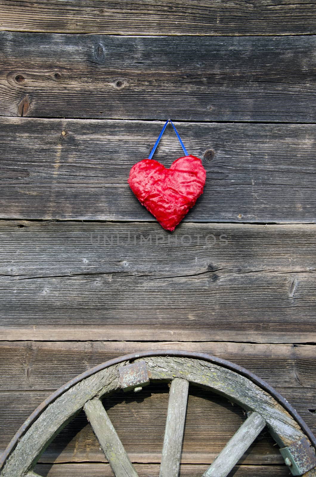 red heart symbol on old wooden bartn wall and horse carriage wheel