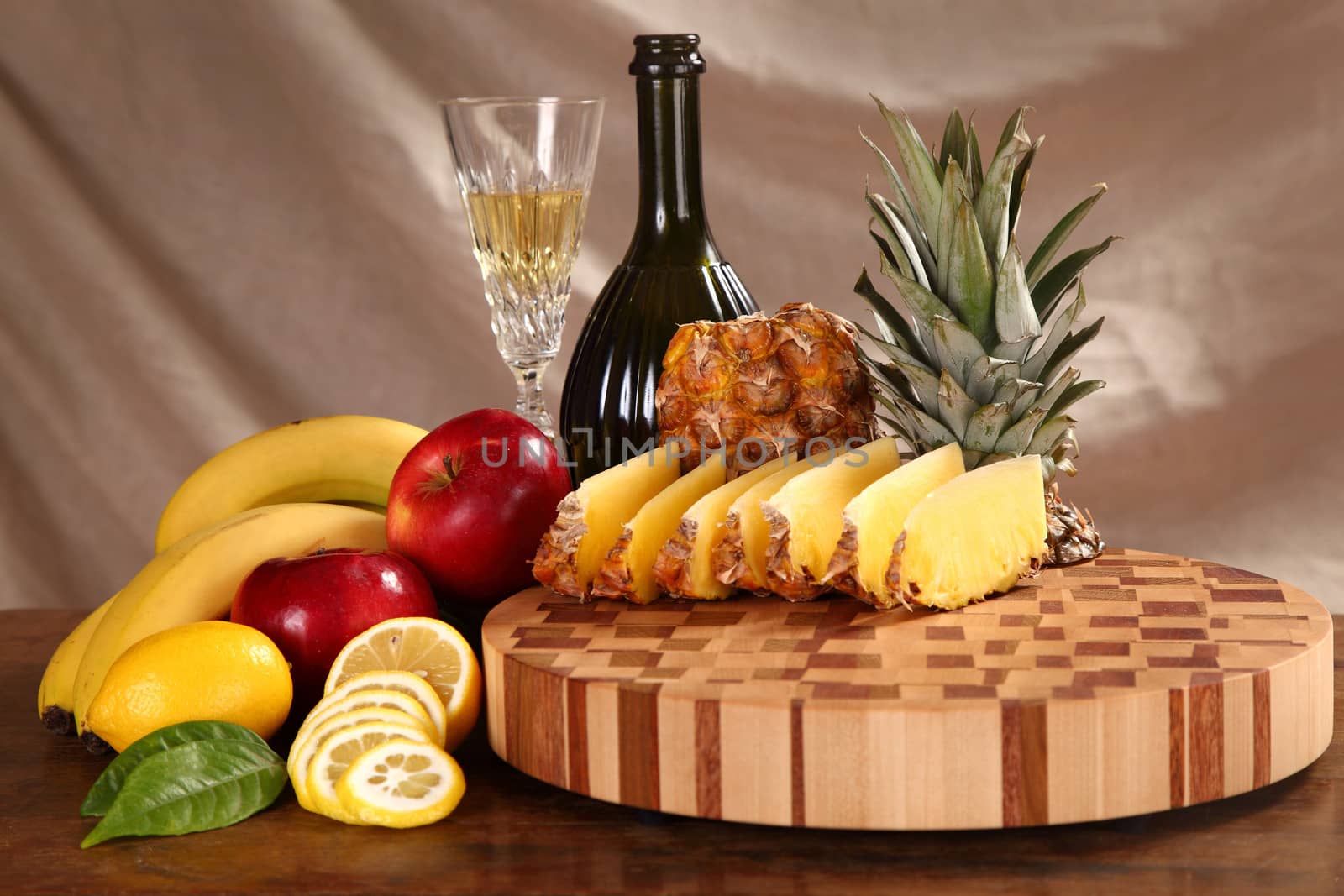 tropical fruit cut by segments, a bottle of wine and a glass on a chopping board
