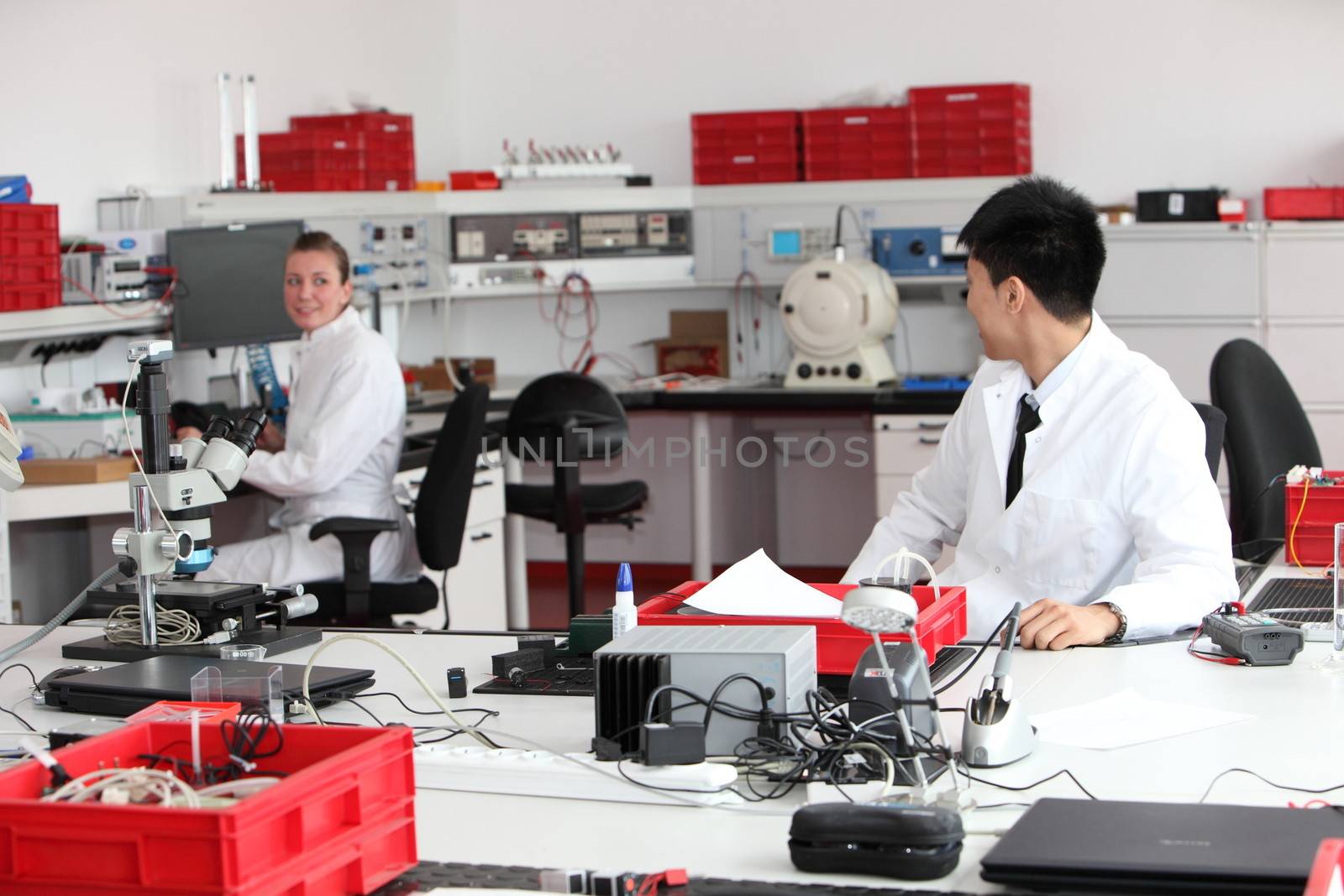 A male and female technician working together in a modern chemical laboratory performing tests for medical or industrial research, analysis or quality control