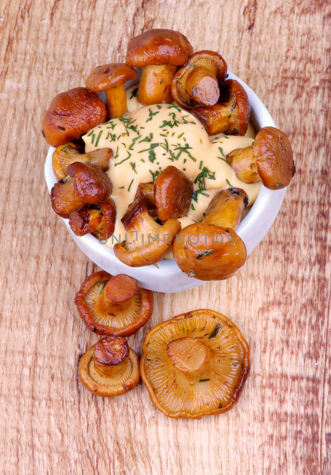 Snack of Delicious Roasted Chanterelles with Cheese Sauce in White Bowl on Wooden background. Top View
