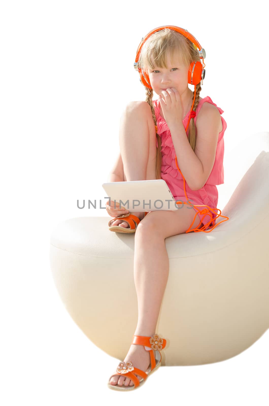 Thoughtful little girl doing her homework on tablet computer and listening lesson in headphones isolated