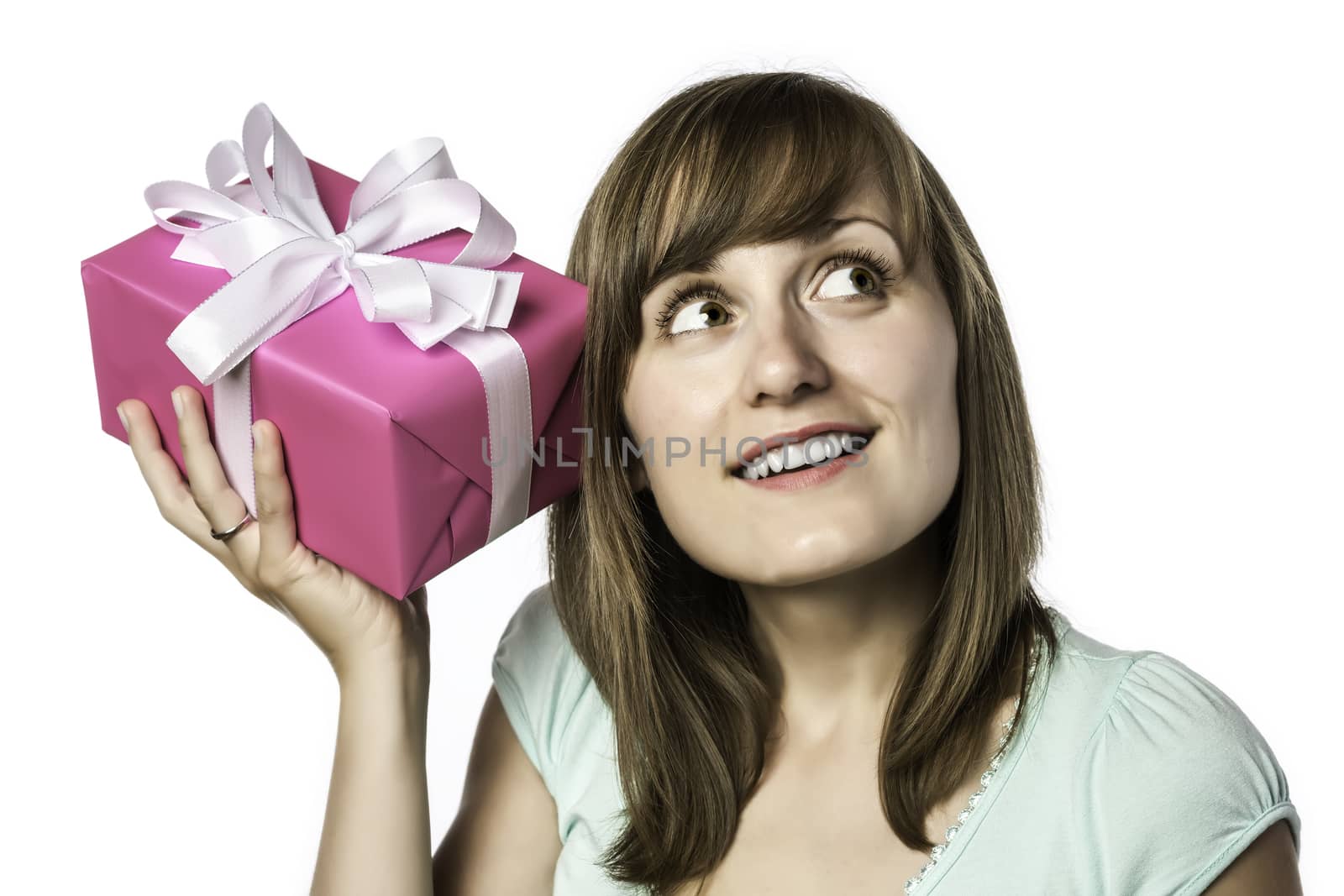 Young pretty girl listens to a gift, isolated on white background