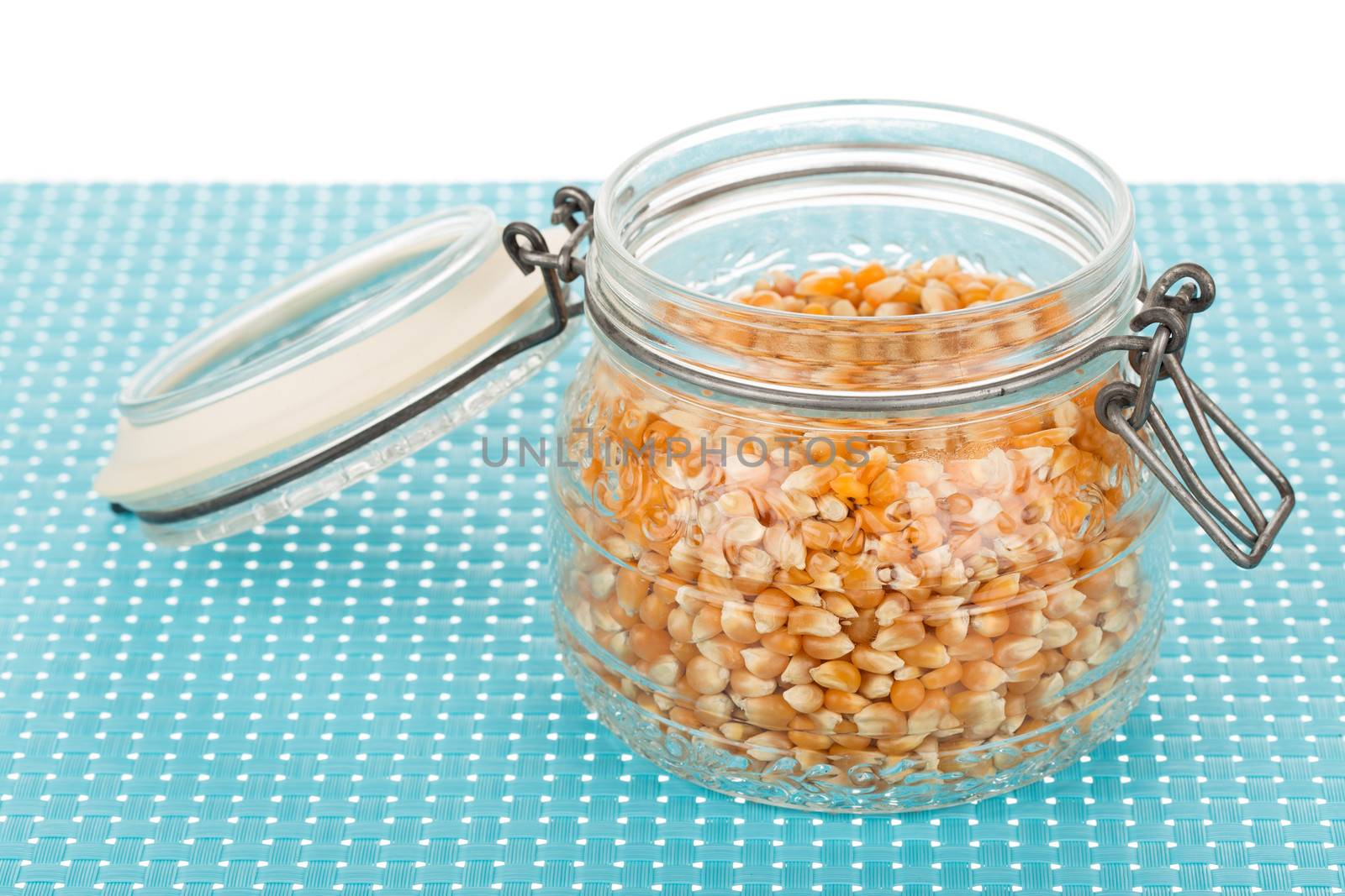 Corn seed in glass jar on blue tablemat.