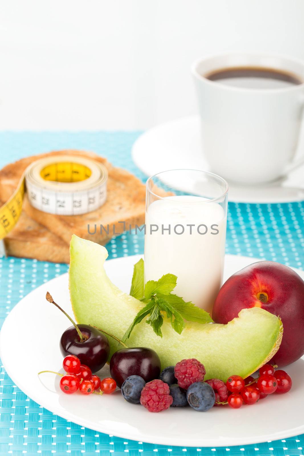 Healthy breakfast with a plate of fresh fruits, glass of milk and cup of coffee.