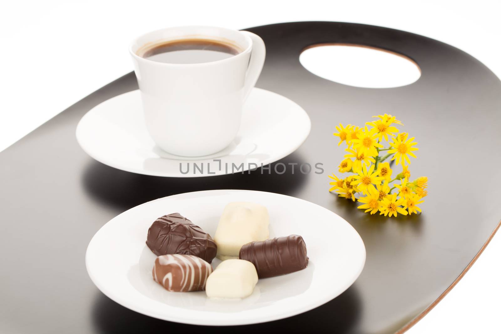 Chocolate assortment in white plate and cup of coffee.