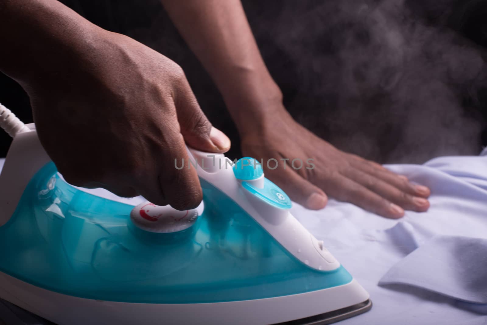 A person ironing a shirt with a steaming hot electric iron