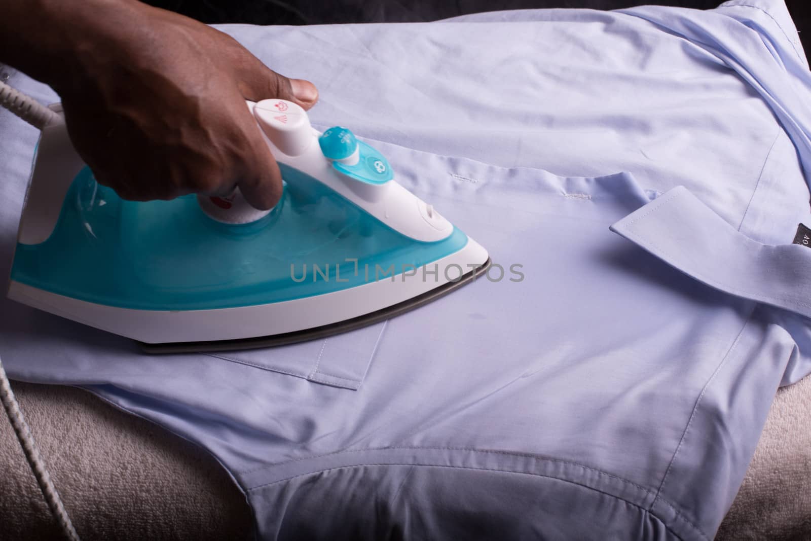 A person ironing a shirt with a steaming hot electric iron