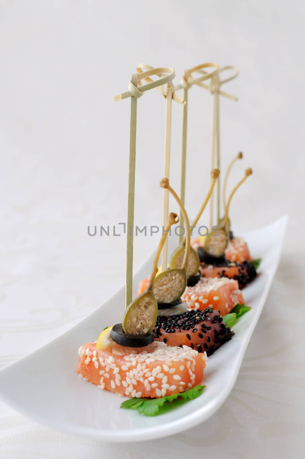 Appetizer of salmon in sesame, olives, lemon and capers