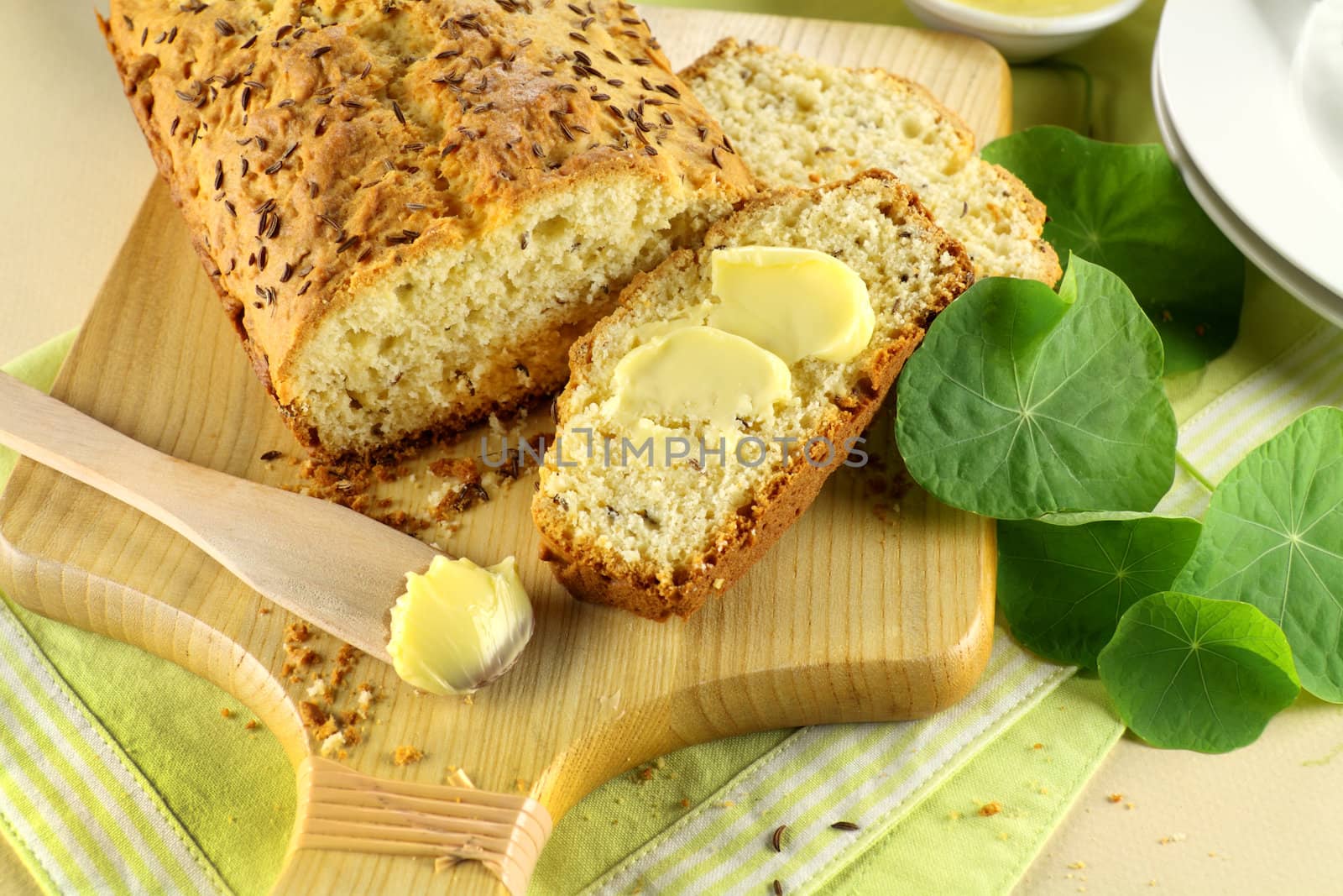Delicious buttered slice of fresh caraway seed loaf ready to serve.