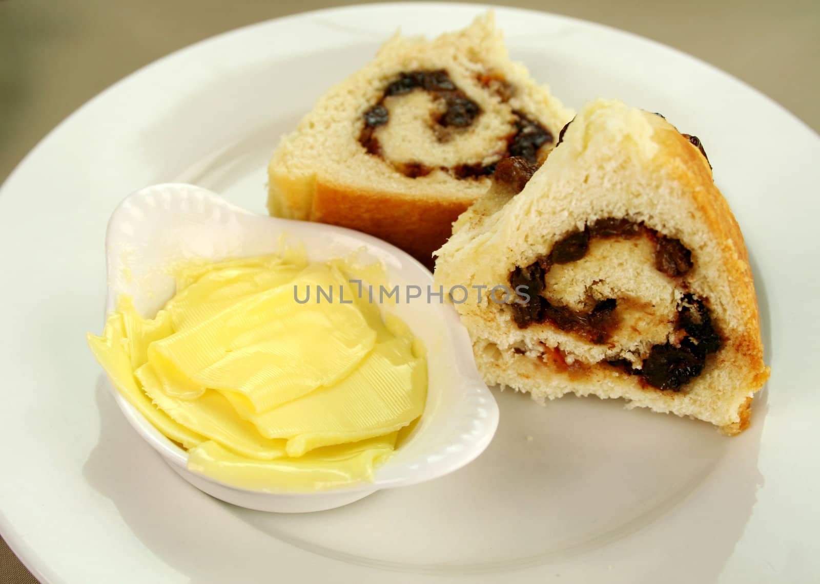 Delicious sliced chelsea bun with dried fruit and butter ready to serve.