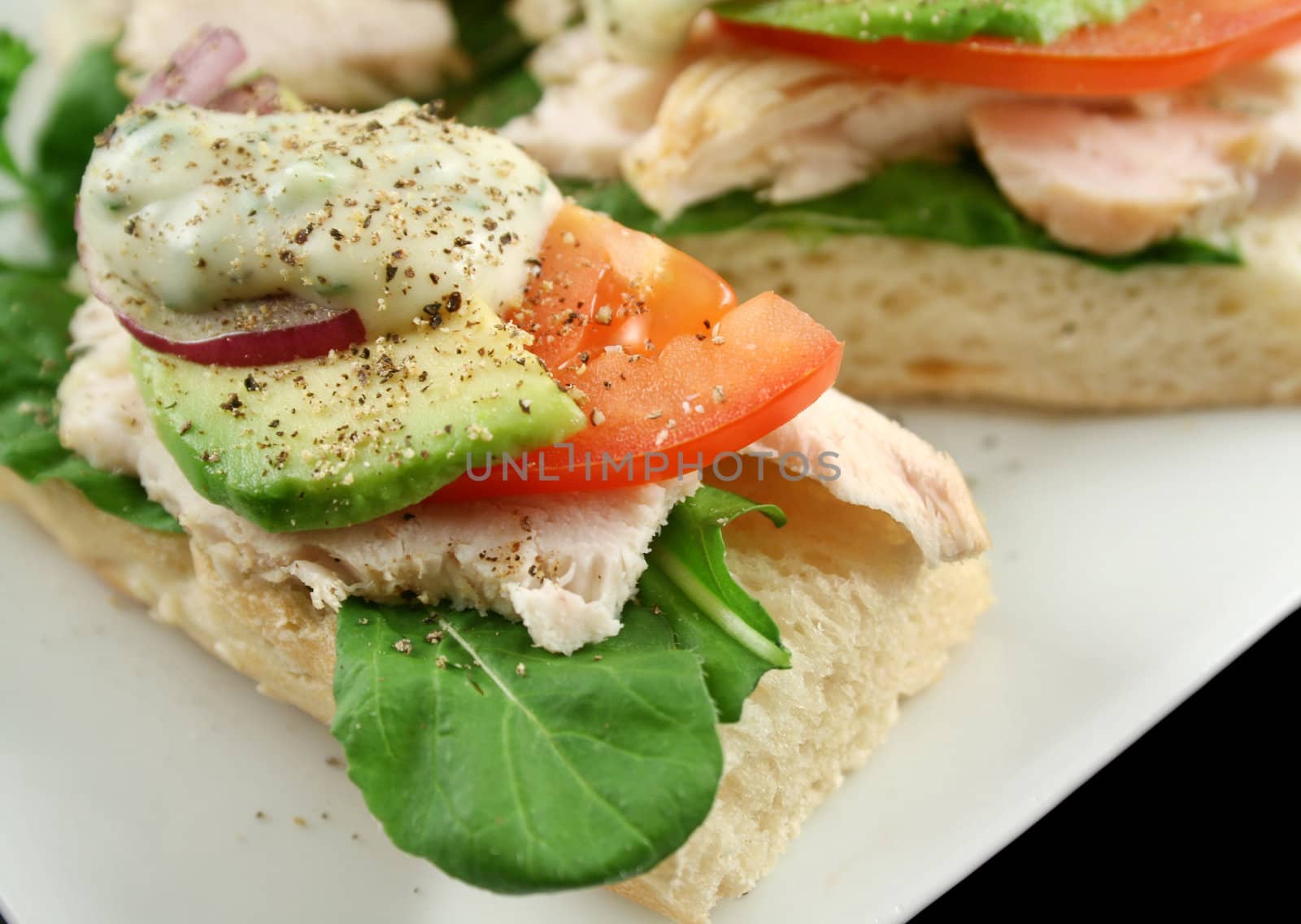 Fresh open chicken finger sandwiches with avocado red onion and mayo with lettuce