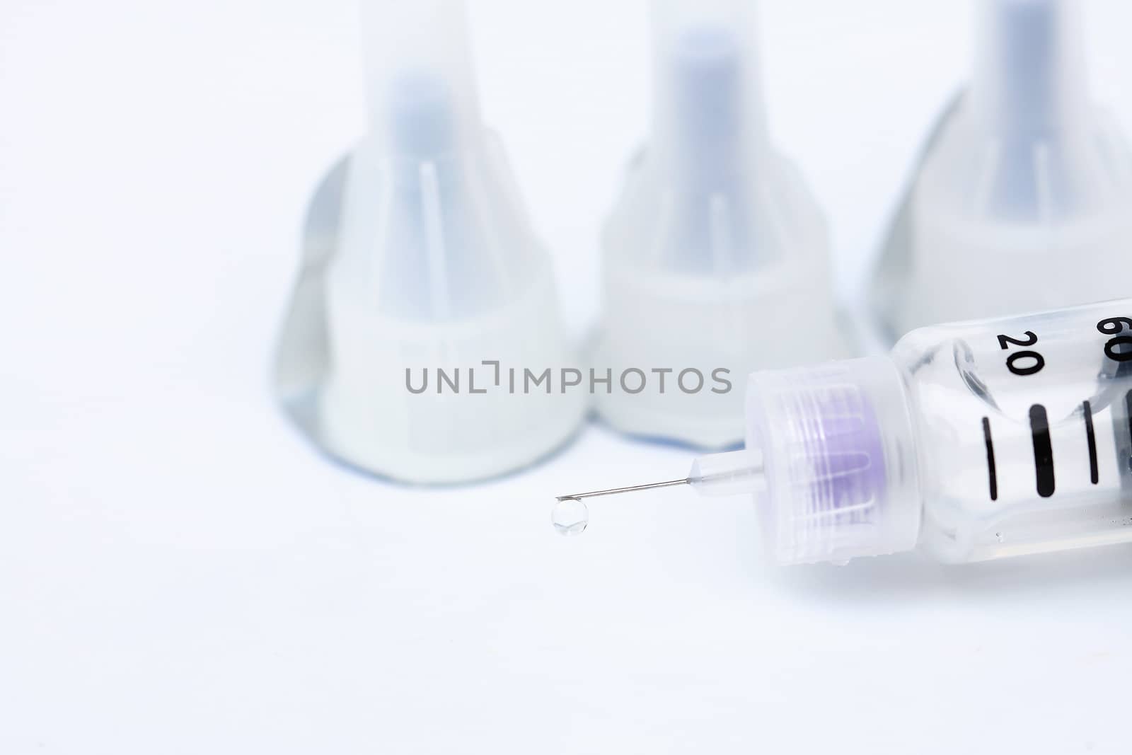 Droplets at the tip of the syringe on a white background