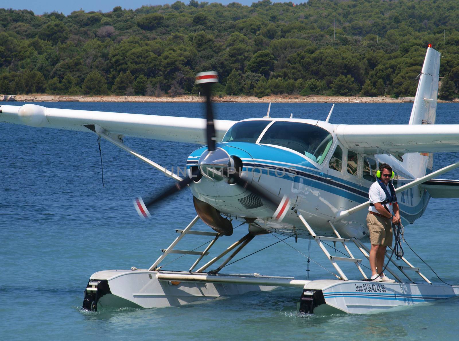 PULA, CROATIA - JULY 1, 2013: Sea plane landing on sea surface connecting two cities: Giulianova, and Pula, on July 1, 2013. After safety  landing the crew member waits with rope in hands for mooring.