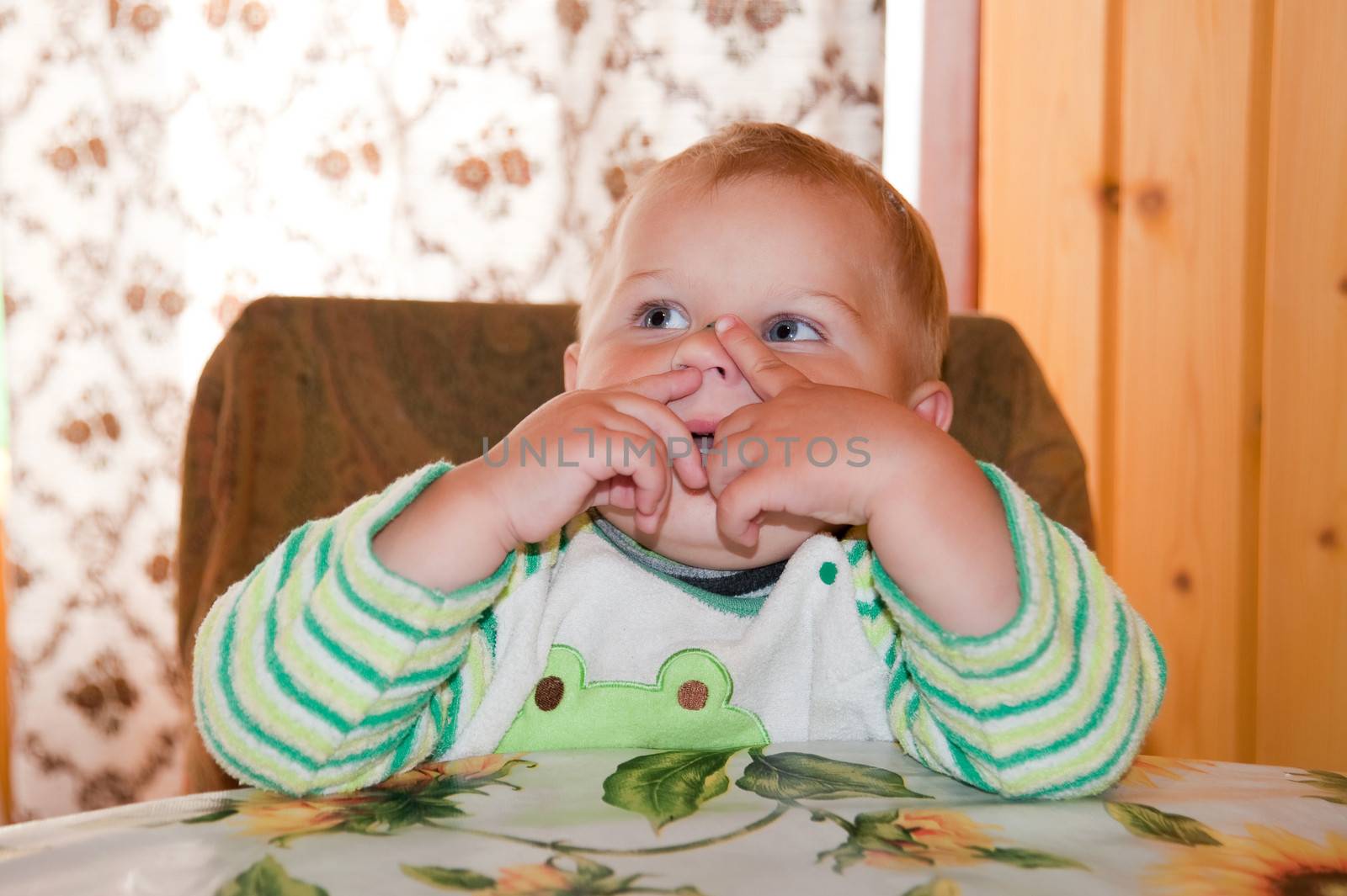 little boy picking his nose at the table