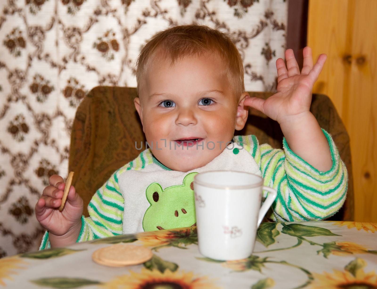 little boy is drinking at a table in the kitchen