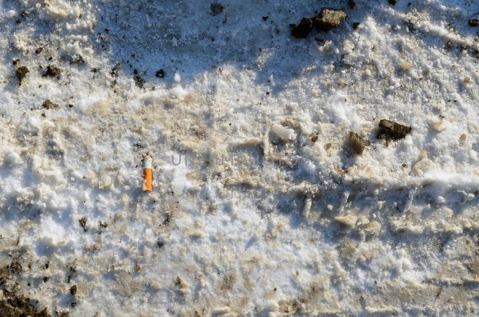 winter snow path closeup background and cigarette butt on ground.