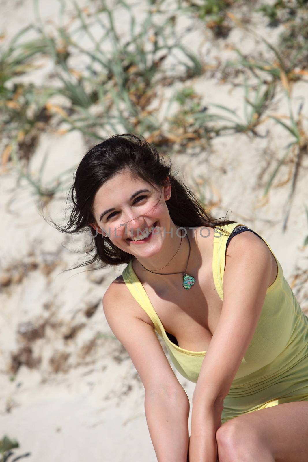 Portrait of a beautiful young brunette woman enjoying the summer sun smiling happily at the camera