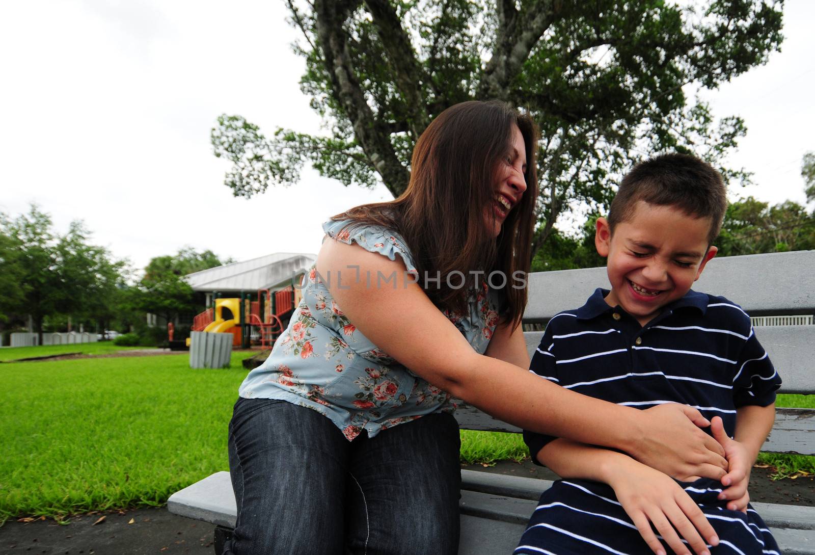 mother tickling child at park and laughing