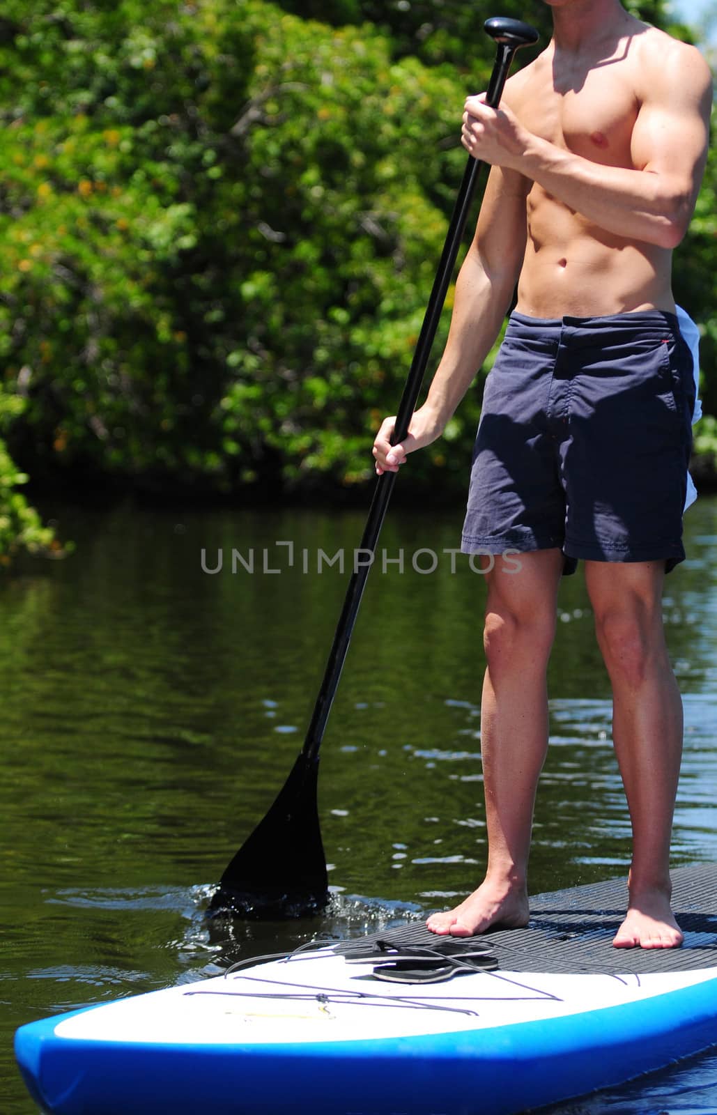 fit man on paddle board in tropical destination