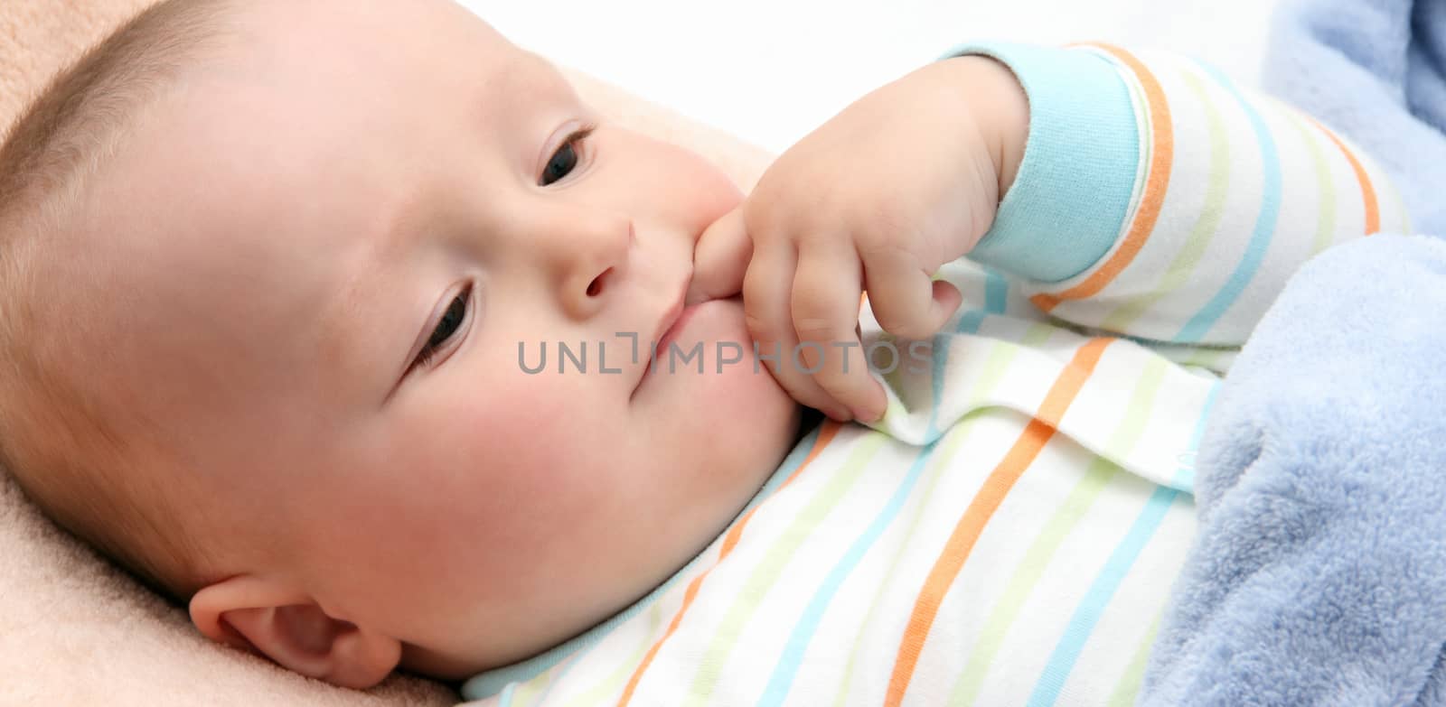 baby in bed with  finger in mouth