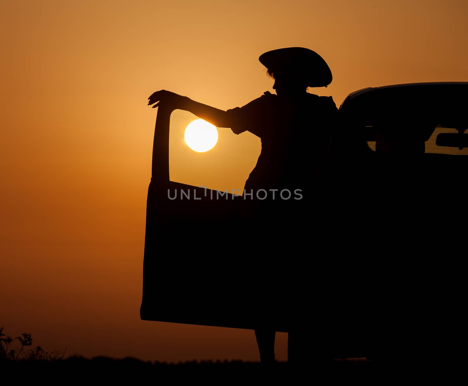 Silhouette woman with hat standing near car by Discovod