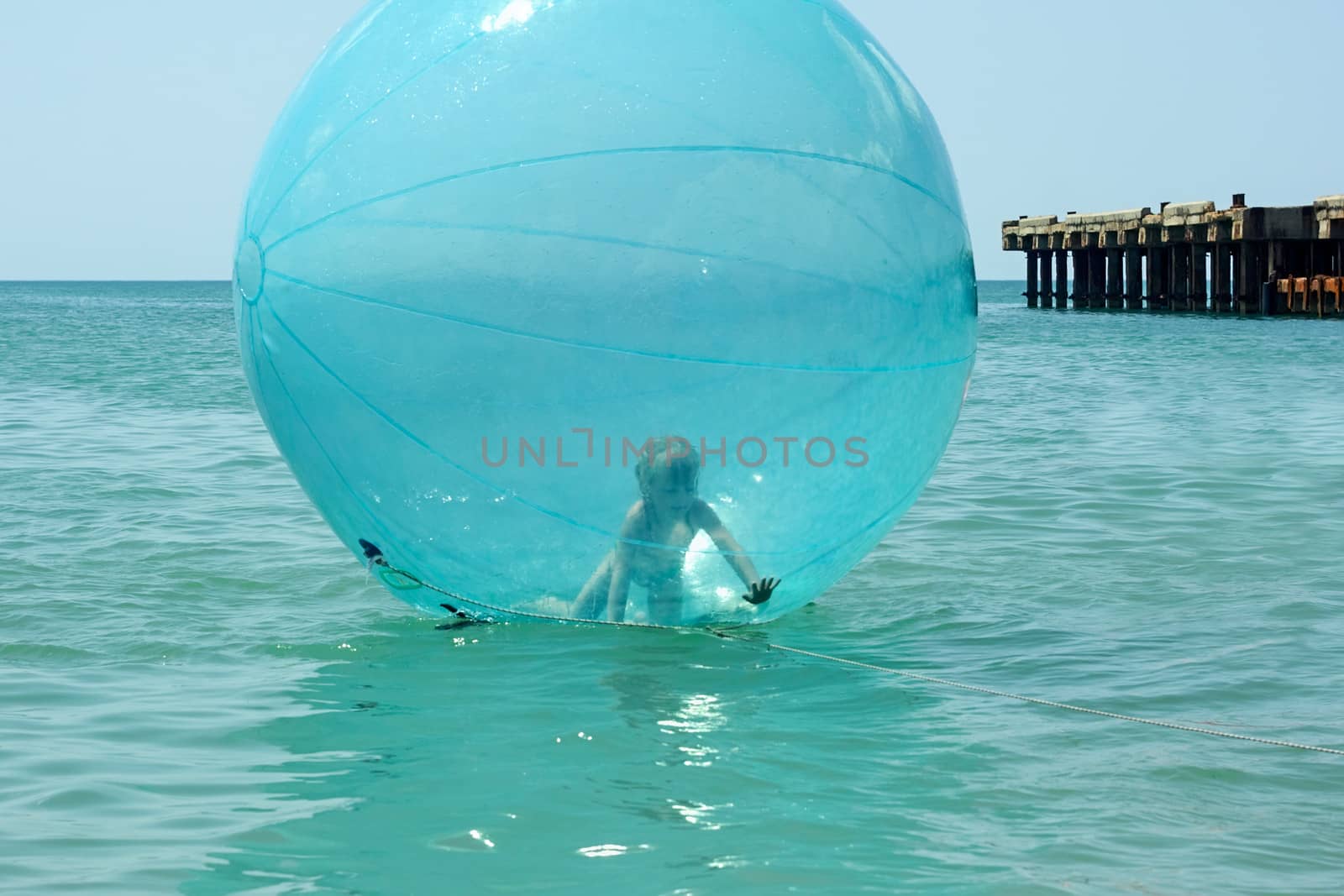 Little girl inside a giant balloon on the sea surface by qiiip