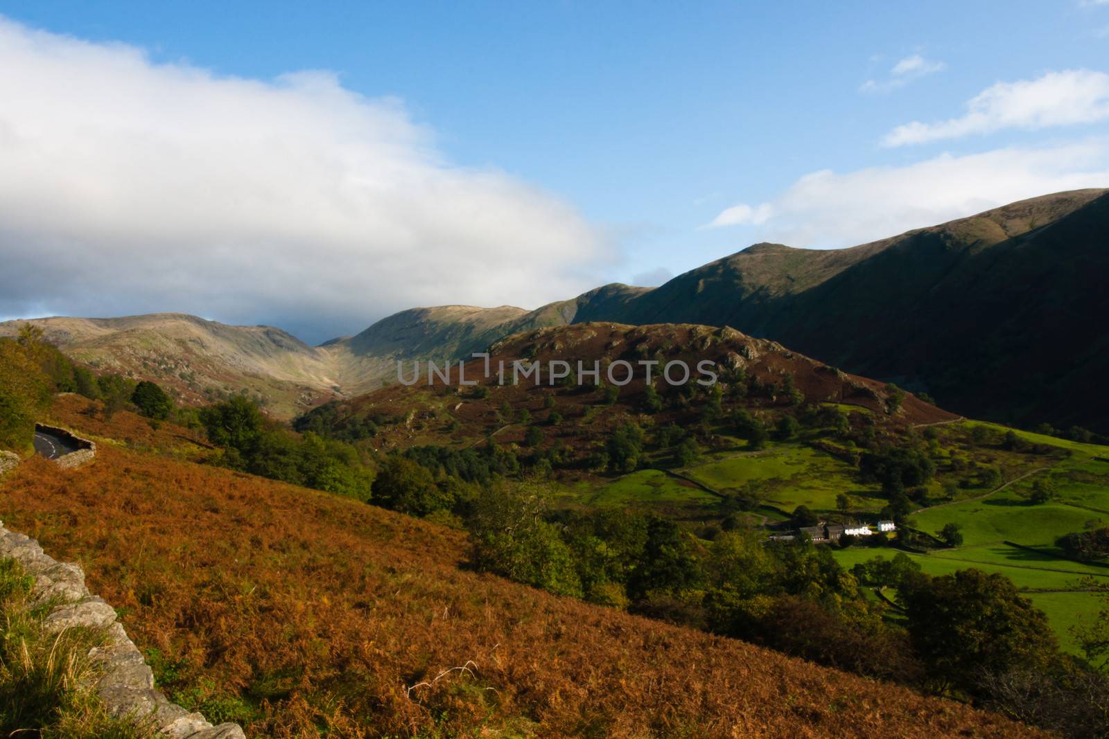 View over hills and valleys in the lake district, cumbria, national park, small stone wall. Taken in Autumn. Lovely clear day with blue sky and white fluffy clouds