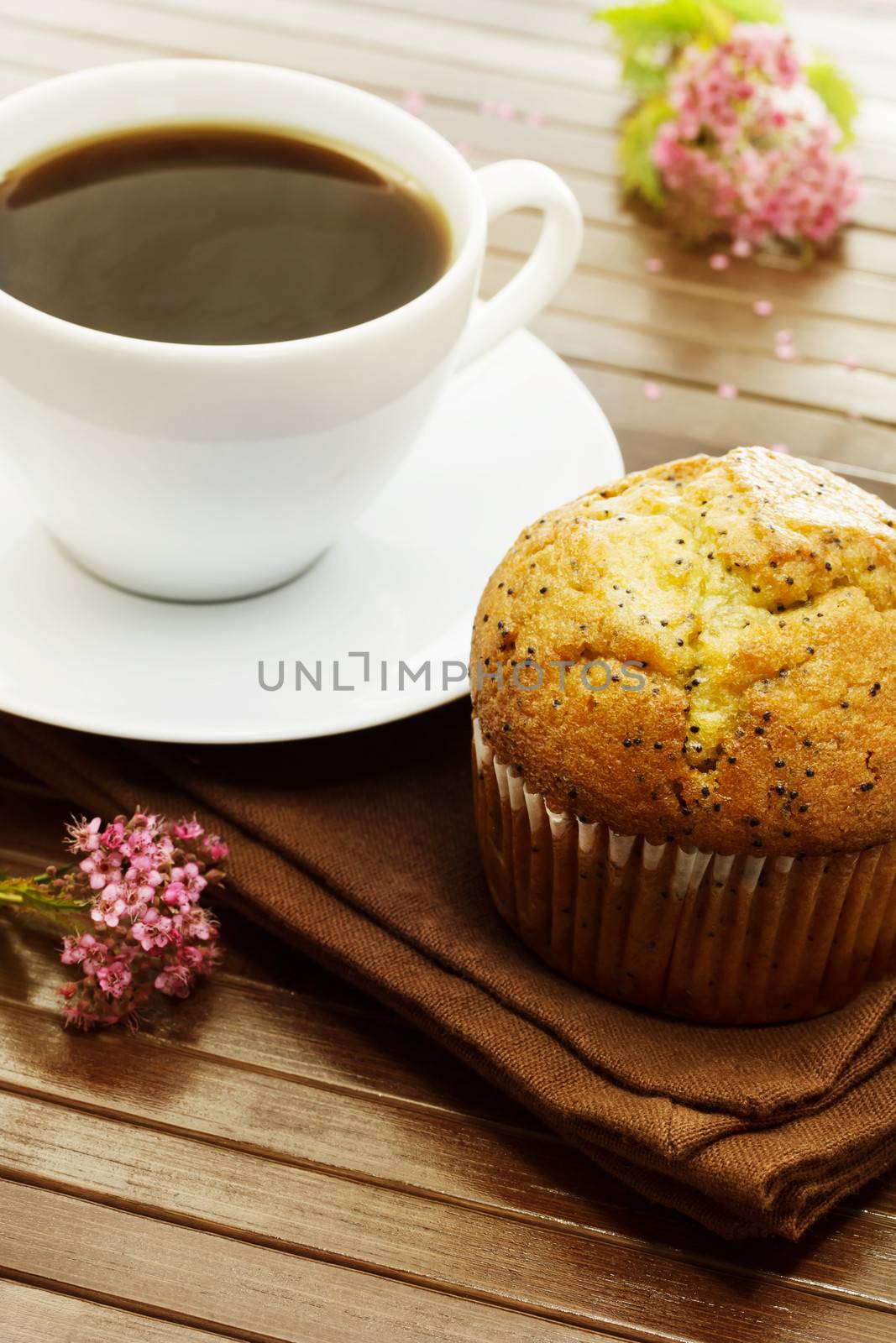 Delicious poppy seed muffins and  a cup of coffee with pink small flowers