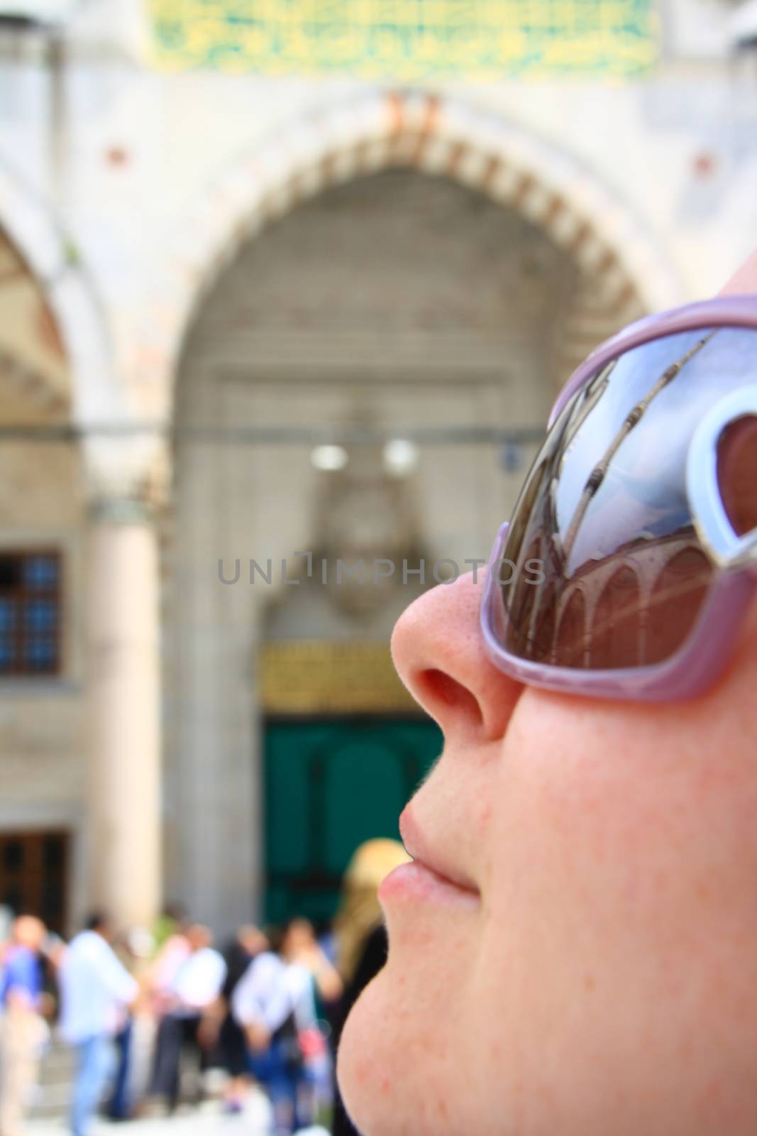 tourist girl in mosque looking minaret and reflection of minaret on sunglass