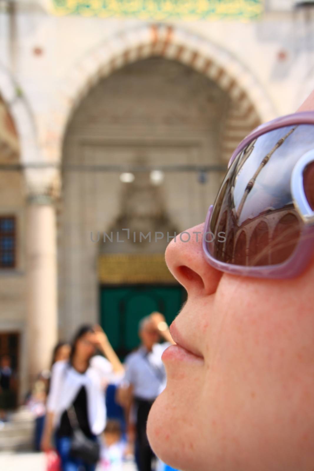 tourist girl in mosque looking minaret and reflection of minaret on sunglass