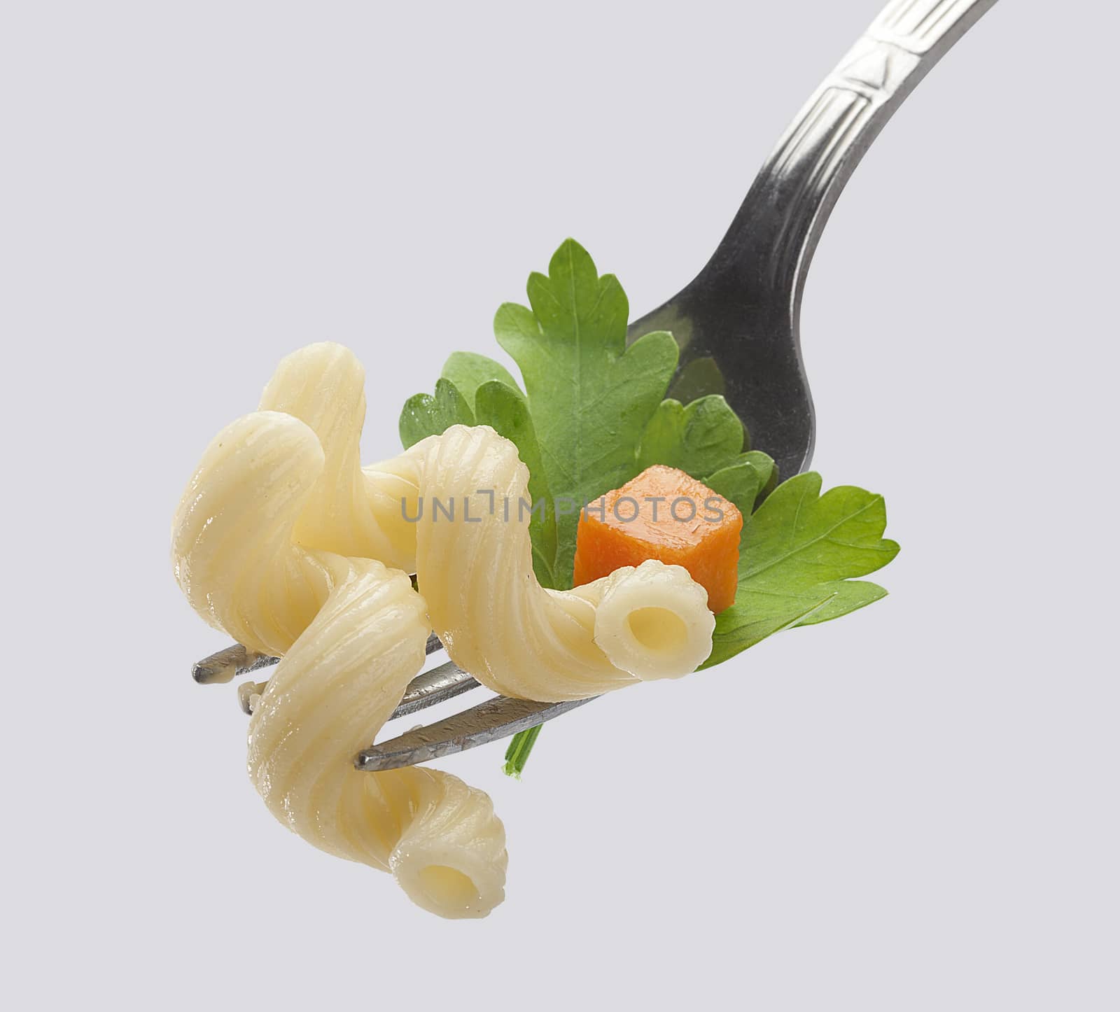 Pasta with fresh parsley and carrot on the metal fork